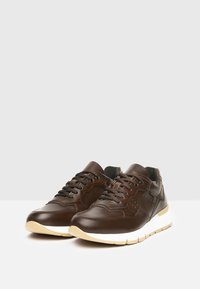 Zapatillas de cuero marrón con un acabado suave, puntera redondeada y suela de goma blanca; cuentan con cordones y perforaciones para una mejor transpirabilidad.