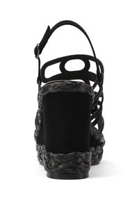 Sandalo con zeppa nera caratterizzato da una texture intrecciata, design con ritagli sul retro e cinturino alla caviglia regolabile. Materiale scamosciato nel tallone.