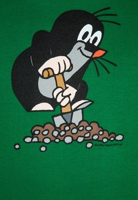 Cartoon mole character illustrated on a green fabric background, holding a shovel and digging in soil with pebbles.