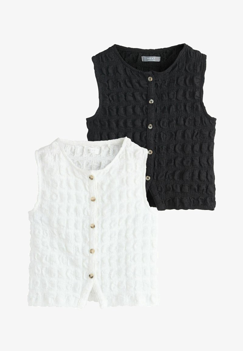 Deux cardigans sans manches en tricot texturé avec boutons sur le devant, un blanc et un noir, posés à plat sans arrière-plan.