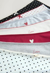 Pile de culottes en coton pour femmes en noir, blanc, gris et bordeaux avec des motifs de cœurs, de petits nœuds et des inscriptions "Love".