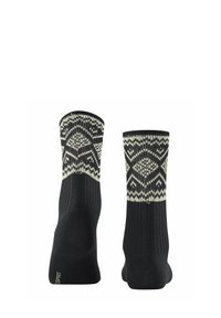 Schwarze Socken mit einem gestrickten weißen geometrischen Muster am oberen Rand. Rippstruktur am Schaft, durchgehend in solidem Schwarz.
