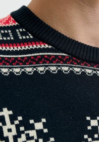 Pullover scuro in maglia con scollatura a coste. Motivi geometrici rossi e bianchi sulle spalle. Tessuto morbido in tutto il capo.
