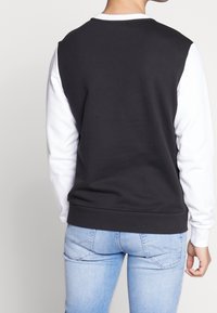 Felpa color block in bianco e nero con polsini e orlo a costine. Texture liscia, collo a giro, e maniche lunghe. Design aderente.