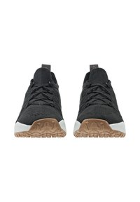 Un paio di sneaker nere in maglia con suole in gomma marrone e intersuole bianche, viste frontalmente su uno sfondo bianco.