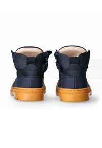 Stivaletti blu navy con suola in gomma color tan. Le caratteristiche includono la chiusura con zip e un rivestimento morbido. Il materiale è una combinazione di tessuto e gomma.