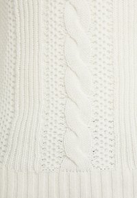Maglione bianco a treccia con motivi testurizzati, caratterizzato da un design centrale a treccia e bordi a coste, realizzato in un filato morbido e spesso.