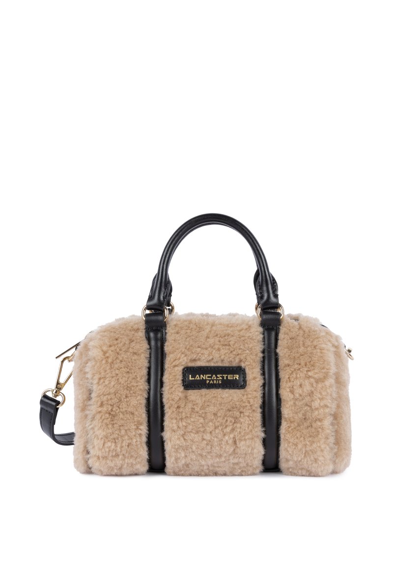 Tan faux fur handbag with black leather accents, dual top handles, and an adjustable shoulder strap. Features a gold logo plate.