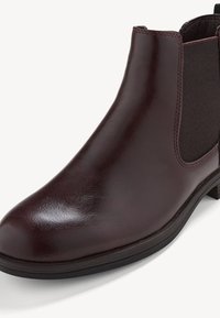 Botte Chelsea en cuir marron foncé avec panneau latéral élastique et petit talon empilé, vue sous un angle avant latéral sur fond blanc.