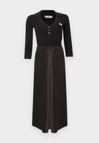 Μαύρο μακρυμάνικο ριμπ τοπ με γιακά και χρυσά κουμπιά, συνδυασμένο με μαύρη σατέν μακριά φούστα με ψηλή μέση, πάνω σε λευκό φόντο.