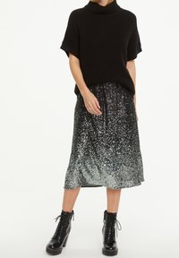 Mustat neulotut lyhythihaiset neuleet ja musta/harmaa ombre-helmet midi-hame, yhdistettynä mustiin nauhakenkiin.