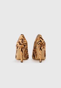 Des chaussures à talons hauts avec un motif imprimé tigre, fabriquées en matériau doux, avec un bout pointu et des talons aiguilles fins.