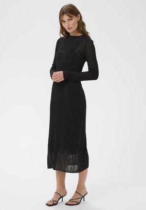 Schwarzes geripptes Strickkleid mit langen Ärmeln, einem Rundhalsausschnitt und einer mittellangen Länge bis zur Wade, ausgestattet mit transparenten Einsätzen und Seitenschlitzen.