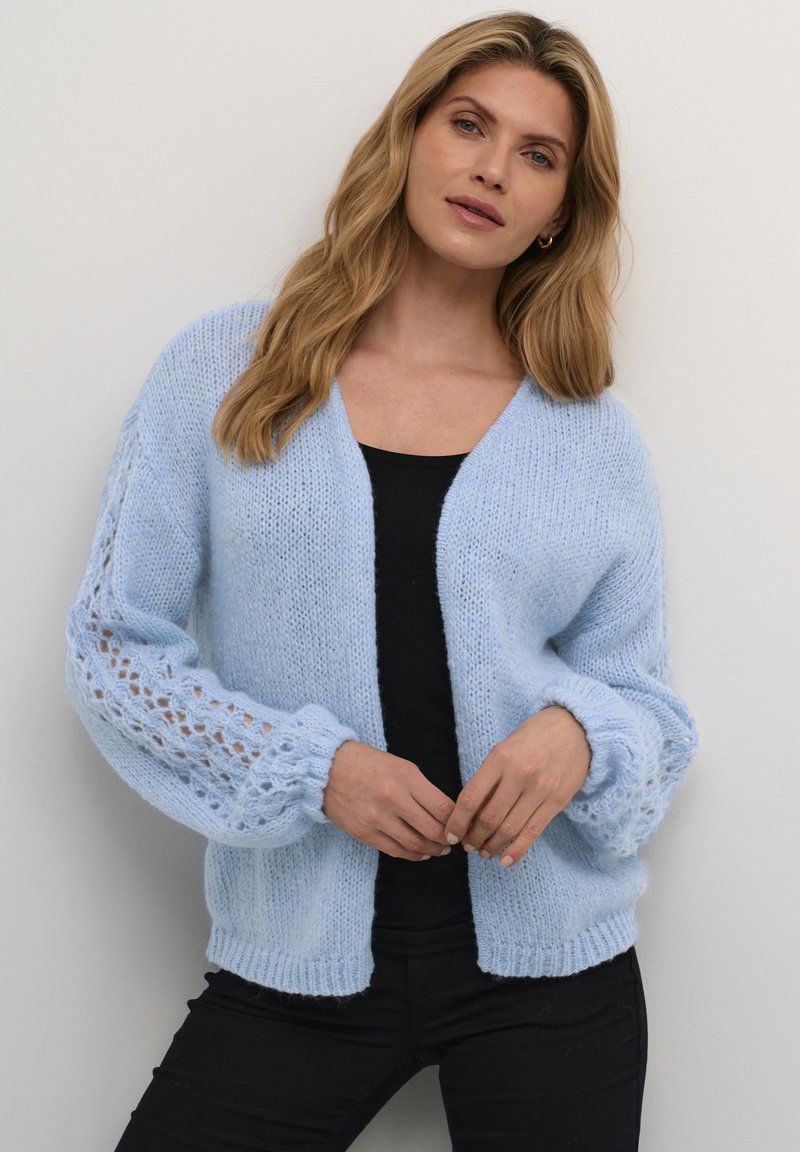 Light blue knitted cardigan with a loose, open front, and textured lace accents on sleeves. Soft, fluffy material.