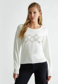 Pullover bianco lavorato a maglia con scollatura rotonda, caratterizzato da un motivo geometrico di piccole paillettes sul davanti e polsini e orlo a costine.