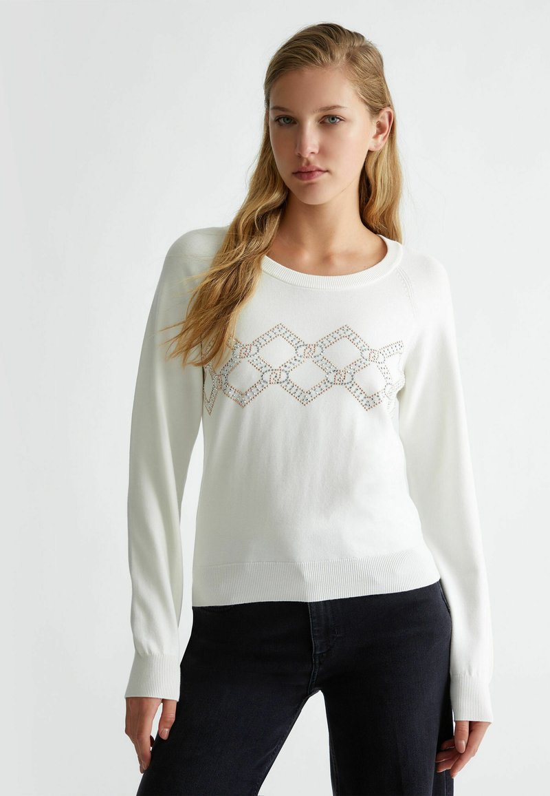 Pullover bianco lavorato a maglia con scollatura rotonda, caratterizzato da un motivo geometrico di piccole paillettes sul davanti e polsini e orlo a costine.