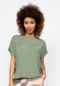Groene t-shirt met korte mouwen, loose fit, zachte stof en een ronde hals. Gestyled met roze pyjamabroeken met een palmbladdecor.