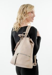 Zaino in pelle beige con chiusura a coulisse, tasca frontale con zip e spallacci regolabili. Texture morbida e design minimalista.