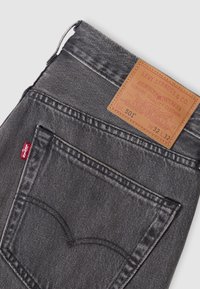 Jean Levi's gris foncé montrant la poche arrière, l’étiquette rouge Levi’s et l’étiquette en cuir beige Levi Strauss & Co. avec la taille W32 L32 et les détails Lot 501.