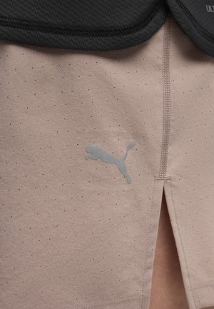 Beige treningsshorts med små ventilasjonshull, sidespalte og reflekterende Puma-logo under svart mesh-stoff i midjebåndet.