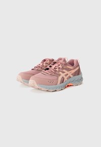 Chaussures de trail running avec un dessus rose et des accents gris, en maille texturée, avec un embout renforcé, un logo orange contrastant et une semelle robuste.