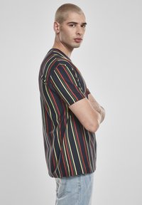 Csíkos póló tengerészkék, piros és sárga függőleges vonalakkal. Rövid ujjú, laza szabású, puha pamut anyagból készült.