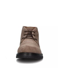 Stivale alla caviglia in suede beige con lacci neri e suola nera, mostrato frontale su uno sfondo bianco.