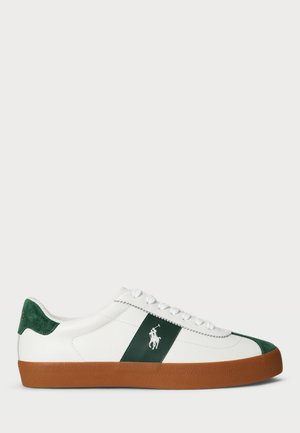 Sneakers bianchi con dettagli in suede verde e una striscia verde scuro. Suola in gomma marrone texturizzata con lacci bianchi e logo ricamato.