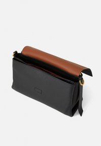 Sort læder clutch taske med en topklap i brunt læder, der har en detaljer i guld metal og en åben indvendig del for nem adgang.