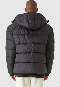 Dunjakke i mørkegrå med hette, med en quiltet design og ribbestrikkede mansjetter. Stoffet har en glatt, teksturert finish.
