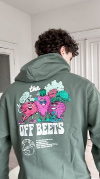 Žalias džemperis su dideliu spalvingu animuotų daržovių grafiniu piešiniu ant nugaros, su tekstu "the OFF BEETS" ryškiu baltu šriftu.