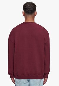 Burgunderfarbener Pullover-Sweatshirt, Mischgewebe aus Baumwolle, lässige Passform, abgesenkte Schultern, gerippte Bündchen und Saum, einfarbige Stoffstruktur, keine sichtbaren Logos.