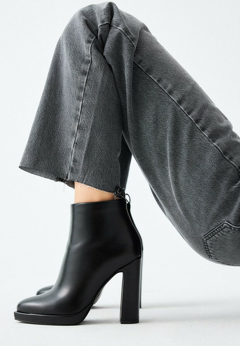 Stivaletti alla caviglia in pelle nera con punta arrotondata e tacco a blocco. Gli stivaletti presentano una texture liscia e una cerniera posteriore per la chiusura.