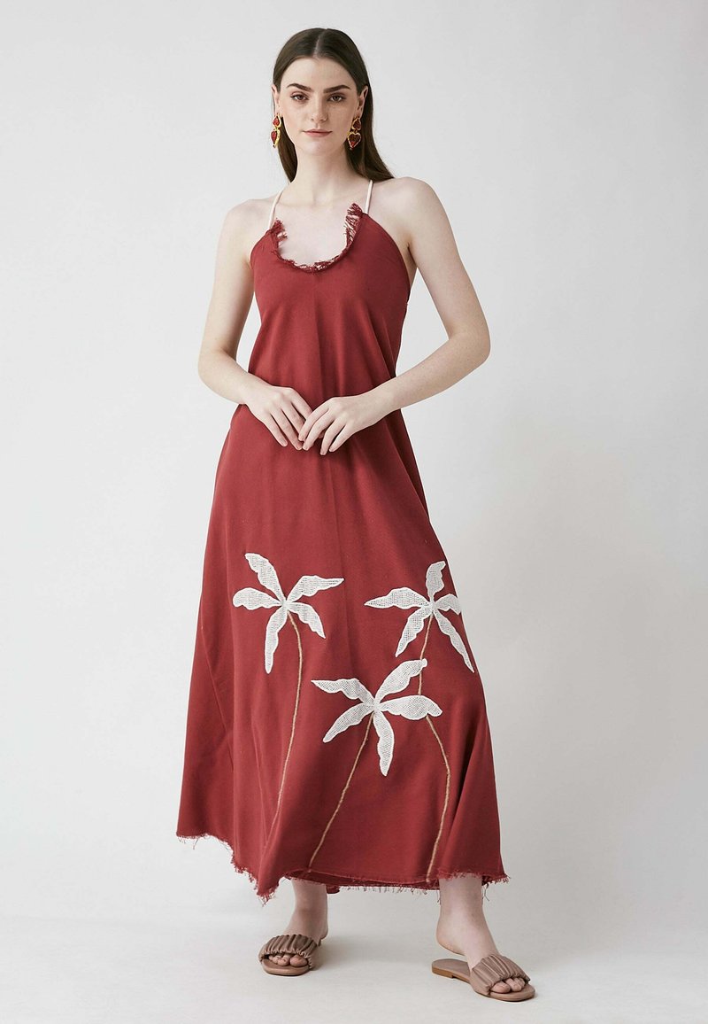Rotes Maxikleid mit einem Fransen-Halsausschnitt und weißen gestickten Palmblättern. Das Material ist weich, das Kleid hat ein fließendes Design und eine lockere Passform.