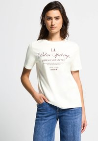 Hvid bomulds t-shirt med korte ærmer, der har maroon grafisk tekst "L.A. Palm Springs Embrace Connection" på forsiden. Casual fit.