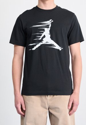 Black cotton t-shirt featuring a large white Jumpman logo in a dynamic pose, set against a plain background. Simple, crew neck design.
