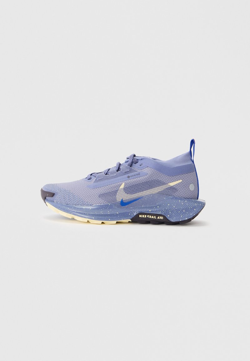 Sapatilha de corrida Nike com uma parte superior em malha roxa respirável, detalhes azuis, pormenores refletivos, sola texturizada e uma entressola almofadada.