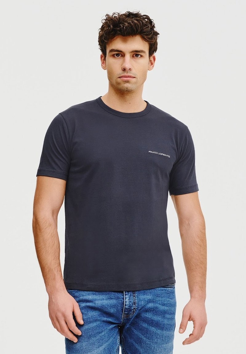 Czarnoszary, krótki rękaw t-shirt wykonany z bawełny, z okrągłym dekoltem i małym logo na lewej piersi. W połączeniu z niebieskimi dżinsami.