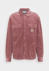 Camisa de pana en color rosa empolvado, con un cierre de botones en la parte delantera, dos bolsillos en el pecho y un pequeño parche con el logo. Tejido texturizado con un patrón acanalado.