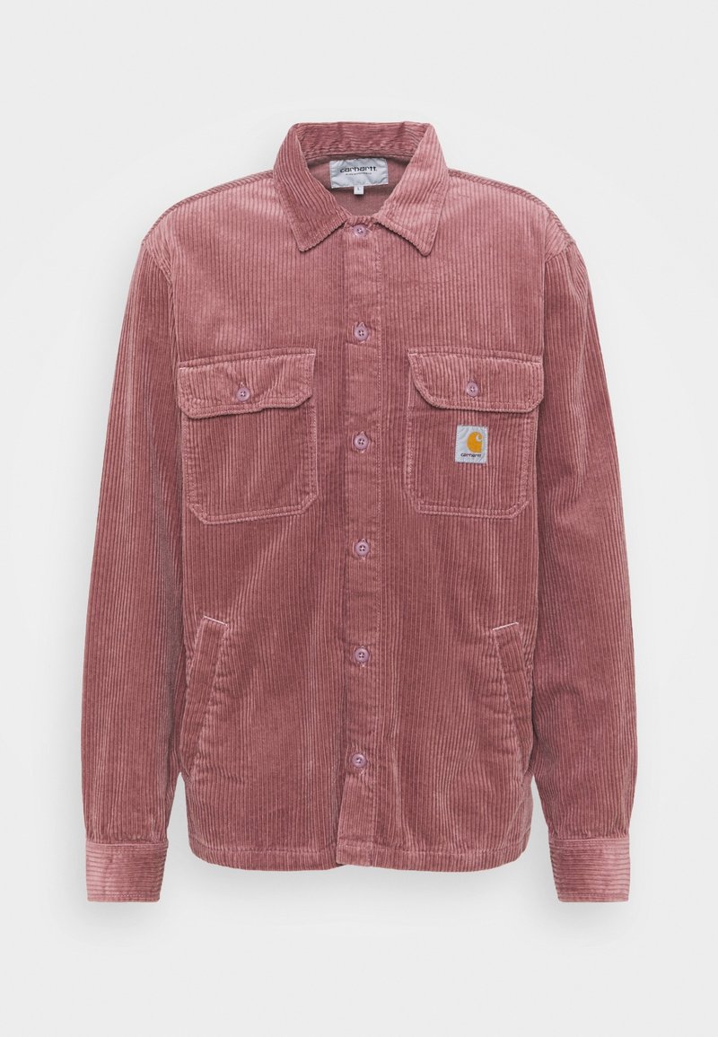 Camisa de pana en color rosa empolvado, con un cierre de botones en la parte delantera, dos bolsillos en el pecho y un pequeño parche con el logo. Tejido texturizado con un patrón acanalado.