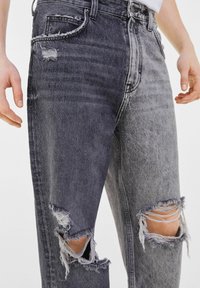 Two-tone denim jeans featuring a faded black and gray color scheme. Distressed knee areas with frayed edges, straight-leg cut, and classic five-pocket design.