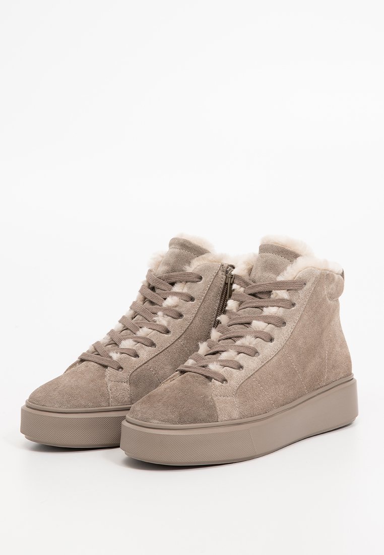 Beżowe zamszowe sneakersy typu high-top o teksturowanym wykończeniu, z futerkiem ze sztucznego materiału oraz płaską gumową podeszwą, z sznurówkami z przodu i zamkiem błyskawicznym z boku.