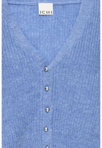 Il cardigan lavorato a maglia blu presenta un colletto a V, cinque bottoni argentati e un tessuto testurizzato. L'etichetta riporta "ICHI". Il design è casual e versatile.