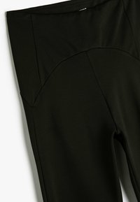 Leggings negros hechos de una tela suave y elástica. Cuenta con una cinturilla alta con un diseño de costura curva y un ajuste contorneado.