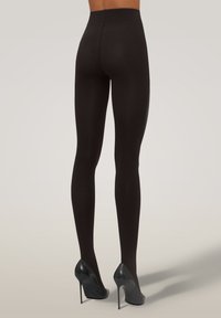Leggings neri con una vita alta, realizzati in materiale liscio e elasticizzato, aderiscono perfettamente lungo le gambe, abbinati a tacchi alti neri.