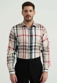 Chemise à boutons ornée d'un motif à carreaux multicolores dans des tons de rouge, gris et noir sur un fond beige clair. Manches longues et design ajusté.