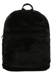 Sac à dos en fourrure noire avec une forme arrondie, des fermetures à glissière et une poignée supérieure. Présente un logo en relief sur le devant et une texture douce.