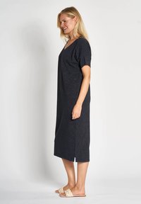 Schwarzes, knielanges Kleid mit kurzen Ärmeln und V-Ausschnitt, mit Seitenschlitzen für Bewegungsfreiheit; gefertigt aus weichem, angenehmem Stoff.