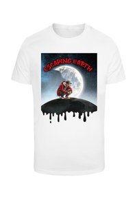 Hvit t-skjorte med en grafisk design av en figur i rød drakt som croucher på en svart bakke med en måne i en stjernehimmel bakgrunn.
