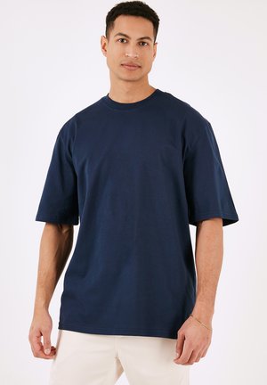 Tricou din bumbac bleumarin, cu decolteu rotund și mâneci scurte, având o croială lejeră și o textură netedă.